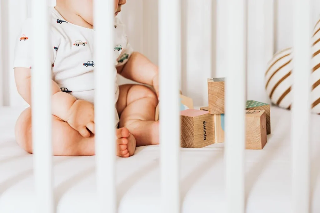 Een baby in de box die nog niet doorslaapt maar aan het spelen is met blokken.